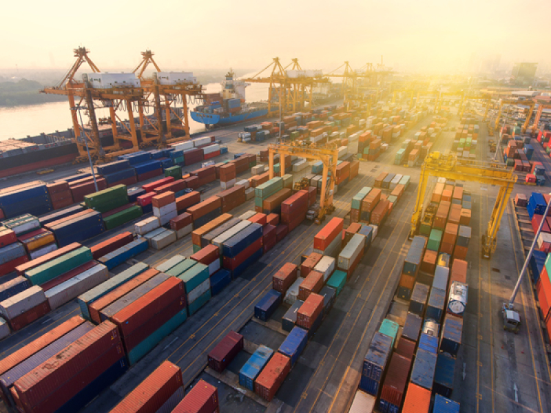 Many sea containers of different colours lined up at a sea port.