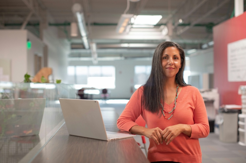 woman wearing red shirt standing in office with laptop